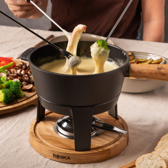 Drie hapjes in een gietijzeren fondueset met gesmolten kaas.